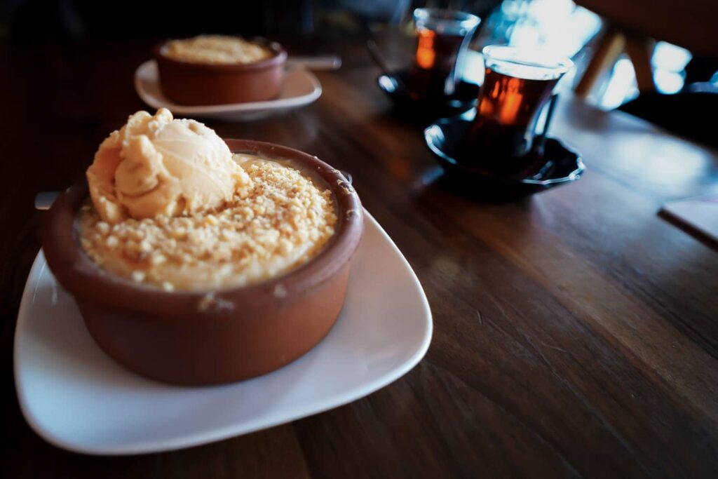 Turkish rice pudding Hamsiköy sütlaç with ice cream on table with tea