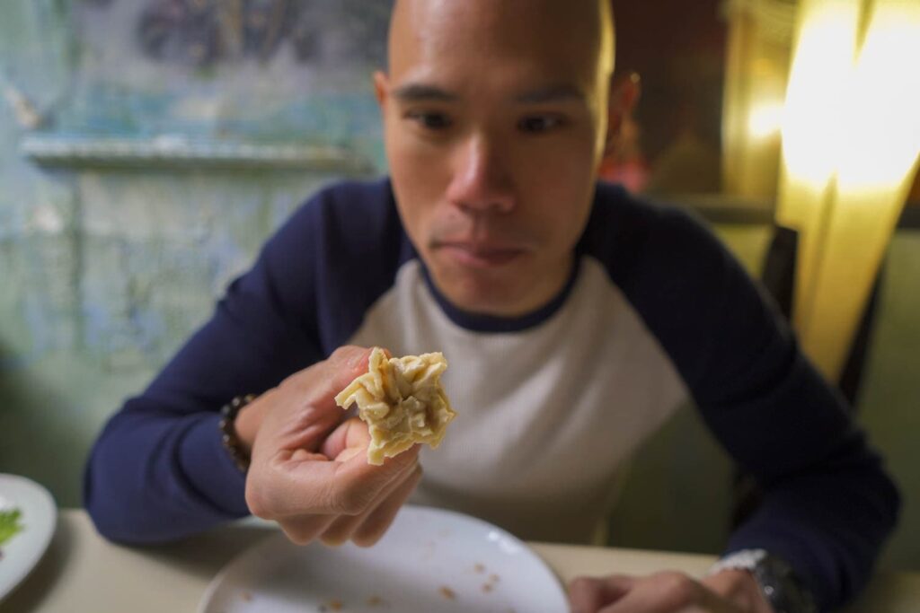 Man holding knob of khnikali Georgian soup dumpling upon finishing eating