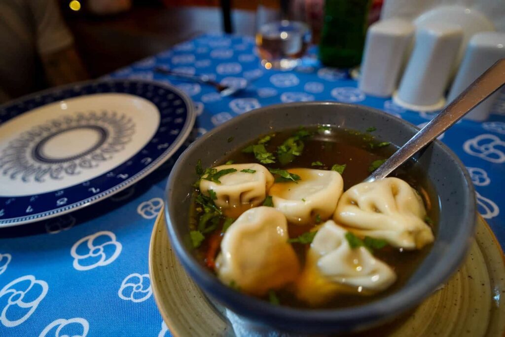 Bowl of mini soup dumplings in a soup broth on table