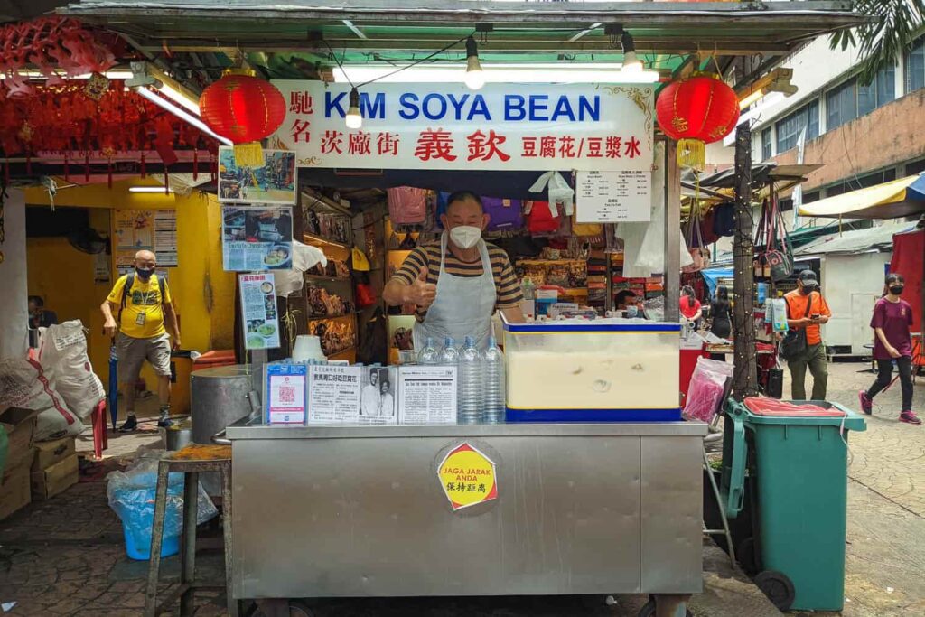 Man owner standing at hawker Kim Soya Bean hawker cart on Petaling Street Chinatown