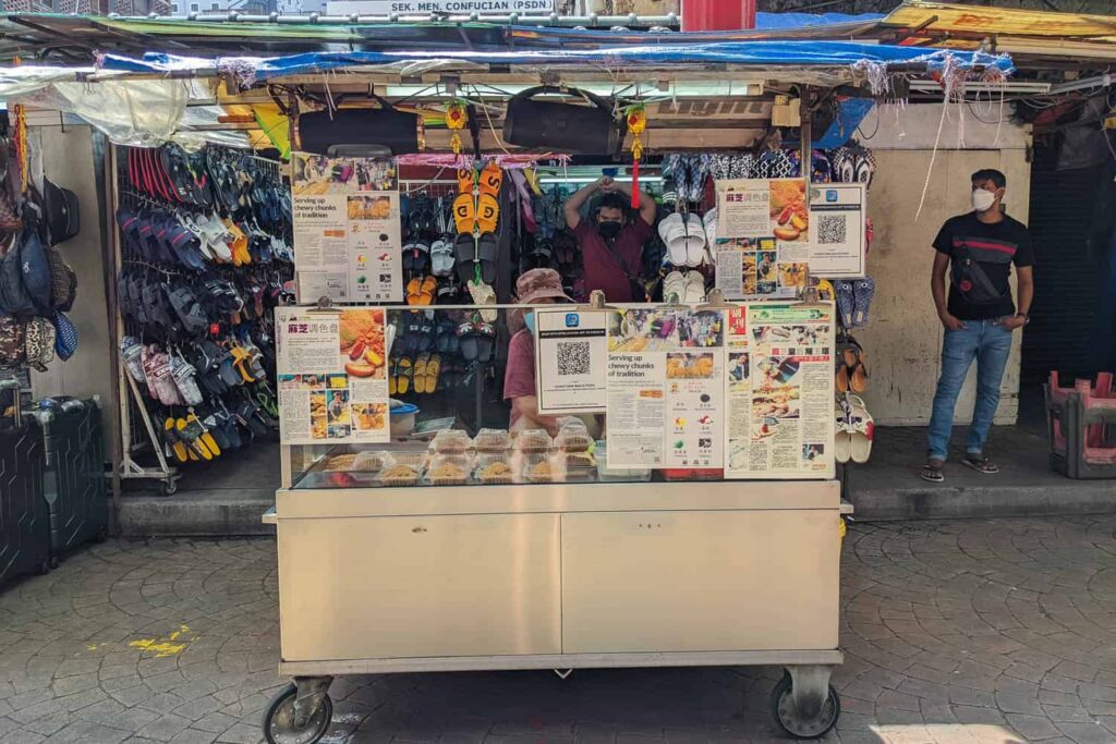 Woman standing at muah chee hawker cart on Petaling Street Chinatown