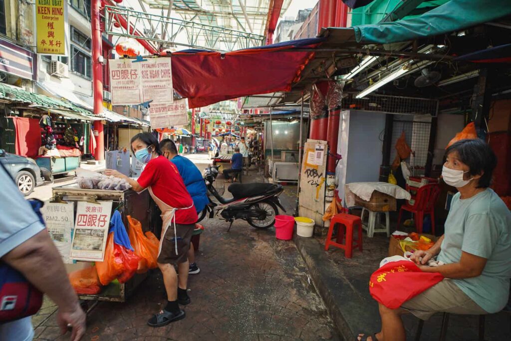 Women standing at a roast duck hawker cart on Petaling Street Chinatown Kuala Lumpur