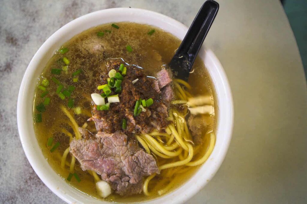 Bowl of noodles with fresh beef and pork floss in broth, sitting on table