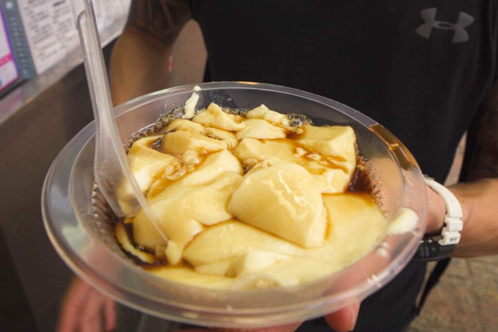 Bowl of yellow tau foo fah soy bean covered in brown sugar syrup