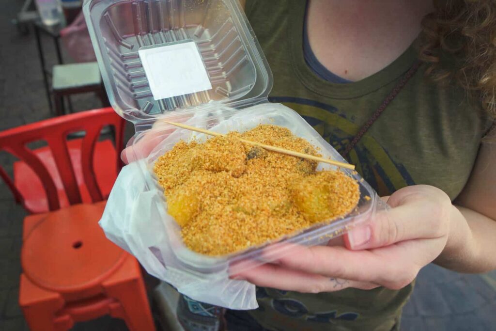 Woman holding box of muah chee with wooden pick for eating