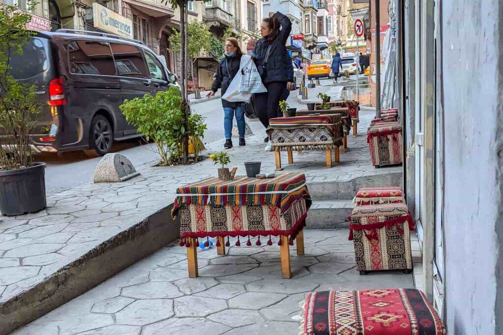 Short wooden tables and stout cushioned stools for drinking coffee on sidewalk