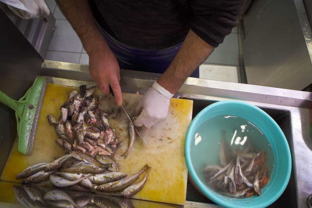 Fishmonger cutting heads off of Black Sea cuisine anchovy hamsi