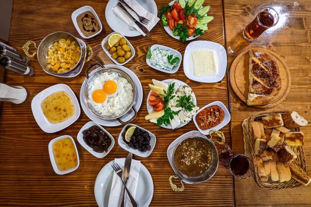 Full Turkish kahvalti breakfast spread laid out on table, eggs, olives, cheese, bread, tea