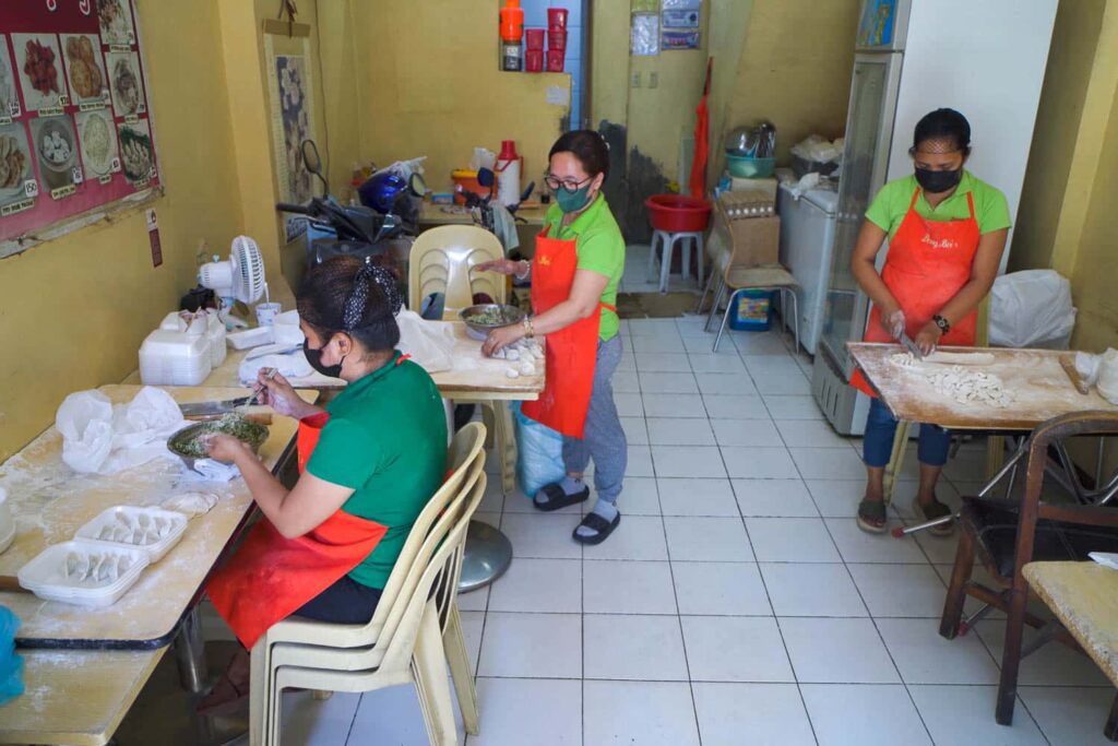 Three women hand making dumplings inside Dong Bei Dumpling