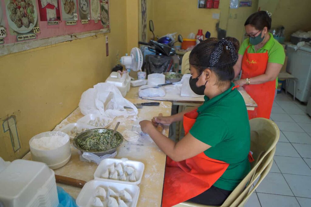 Women filling dong bei dumplings with pork and chives