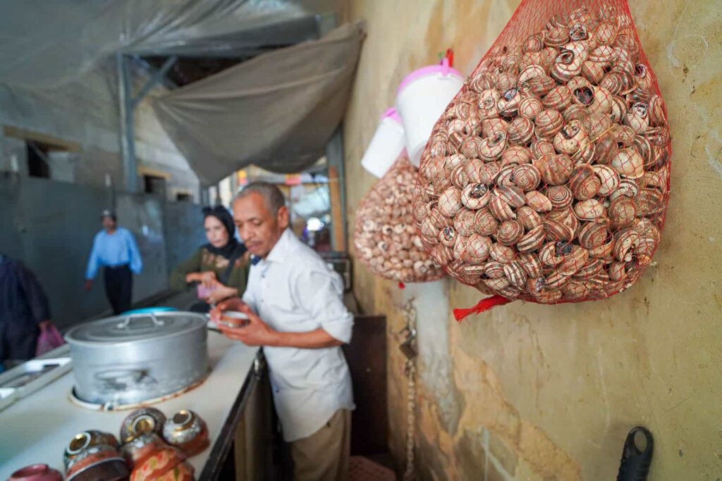 Moroccan snail soup vendor with bags of snails hanging on wall