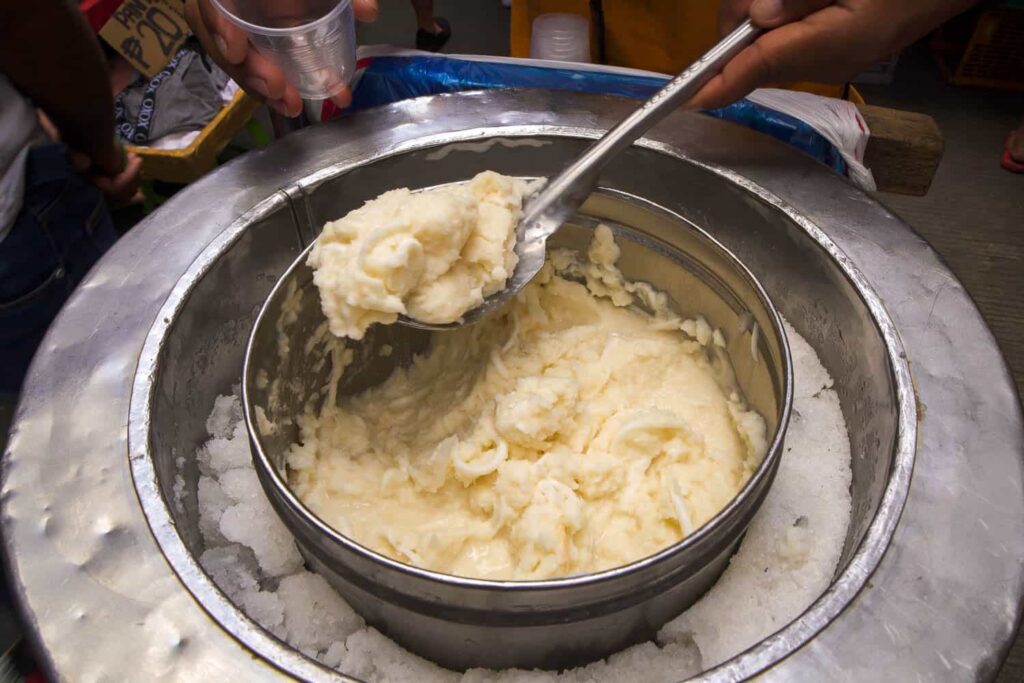 Fresh creamy coconut ice cream in large metal cooling container