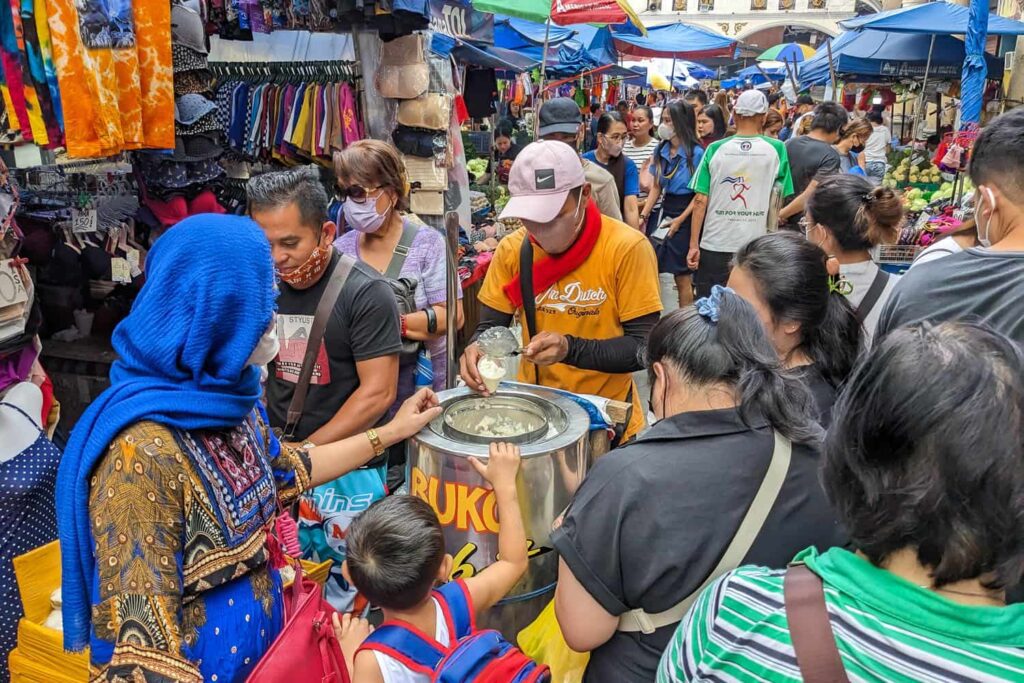 Busy street in Quiapo market with vendor selling best coconut ice cream