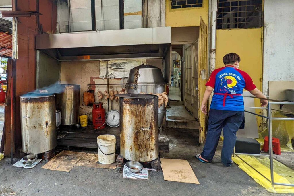 Wong Sifu grandson standing with coal fired drums back of restaurant
