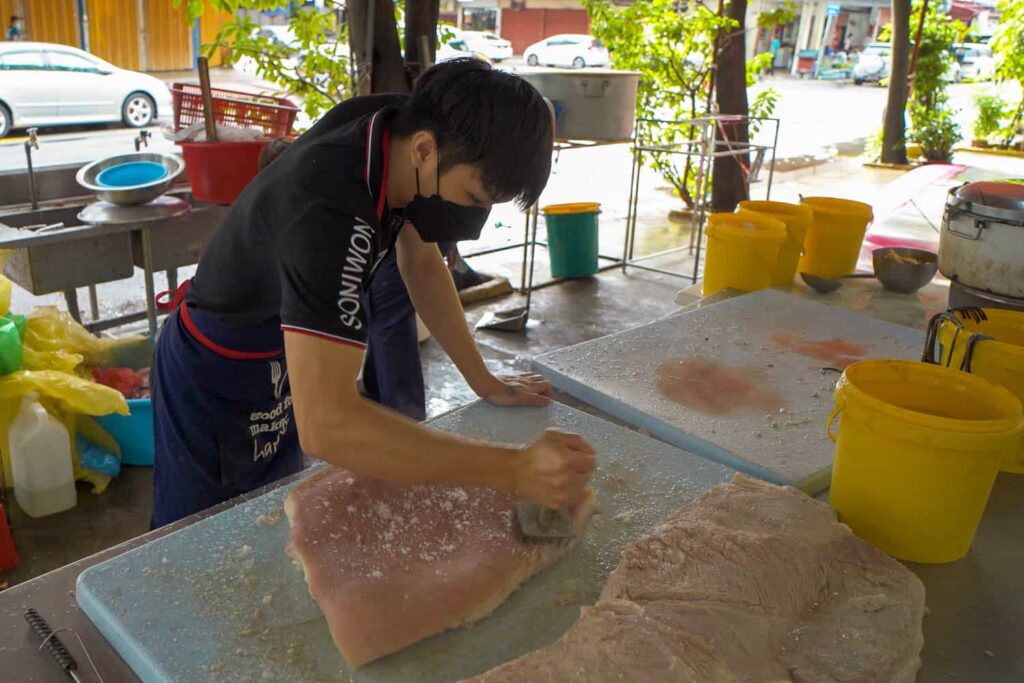 Wong Sifu grandson using meat mallet on best siu yuk in kuala lumpur crispy pork belly