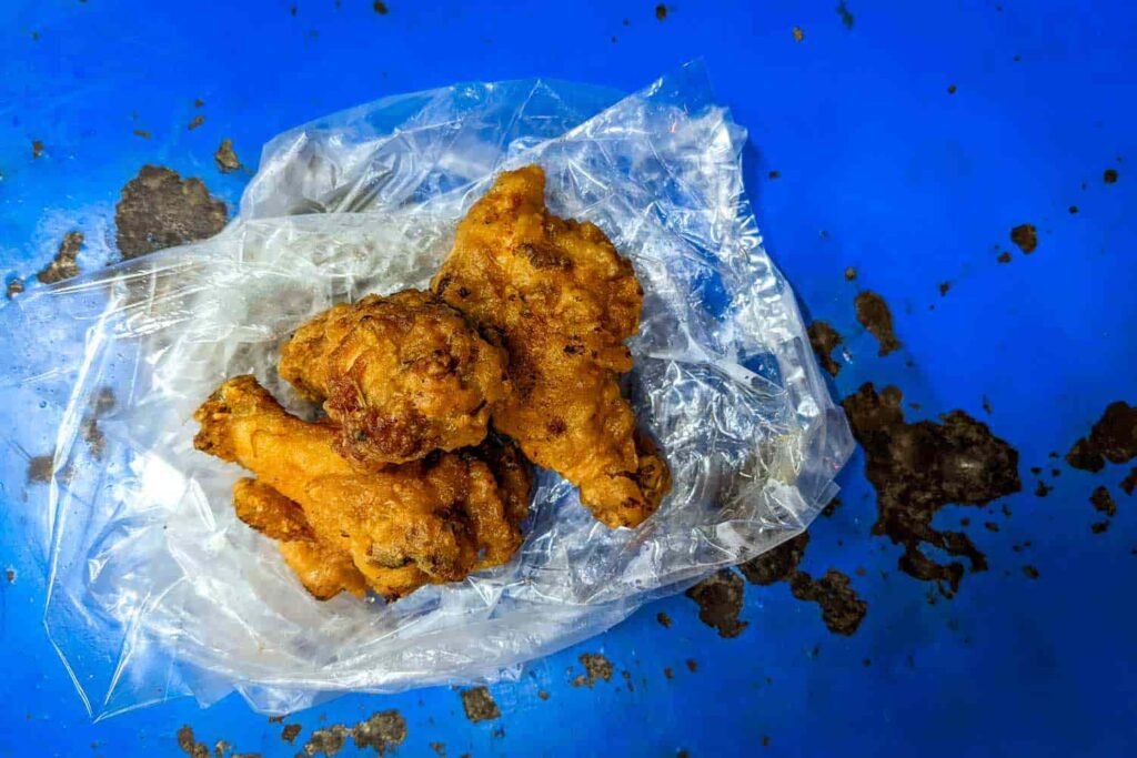 three pieces of Thai street food fried chicken on blue metal table