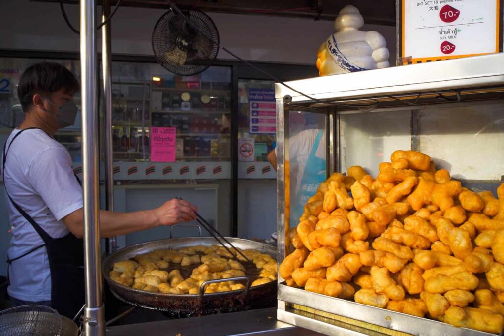 Michelin guide man sitting on metal frame full of patongo Thai savoury donuts