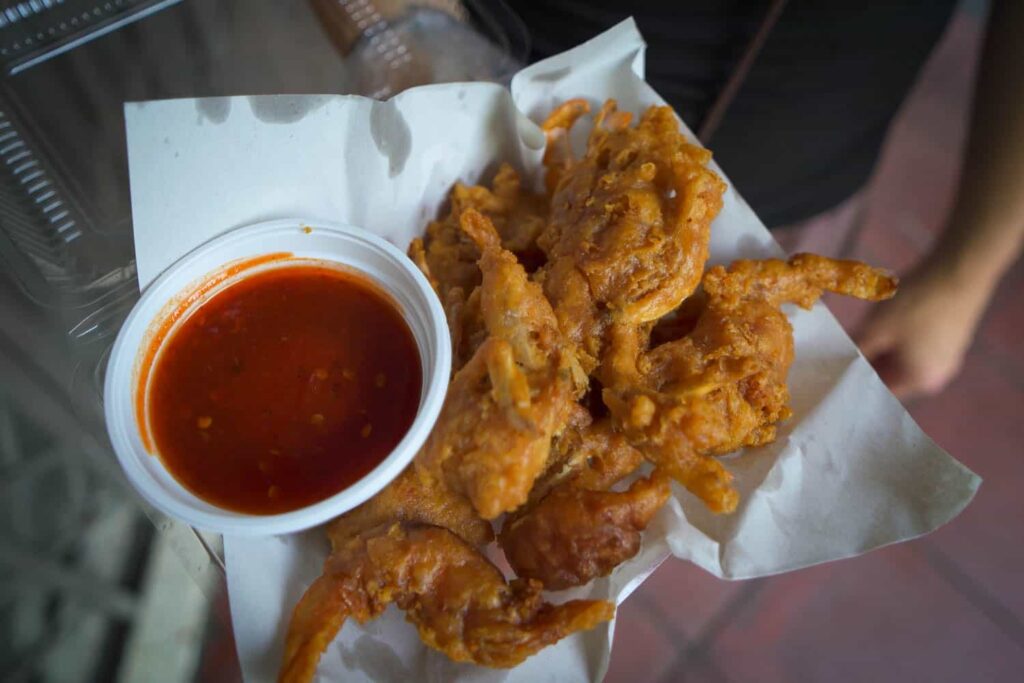 Paper container of fried soft shell crab with side of chilli sauce