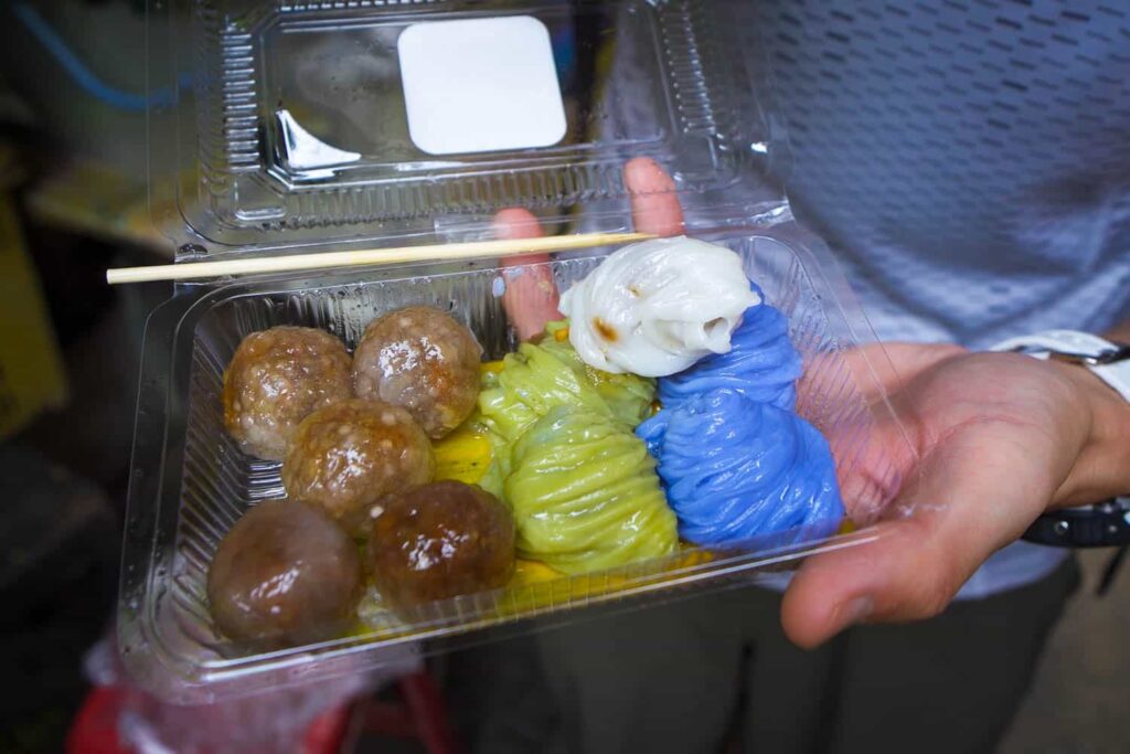 Plastic container of clear, green, white and blue balls of saku sai moo