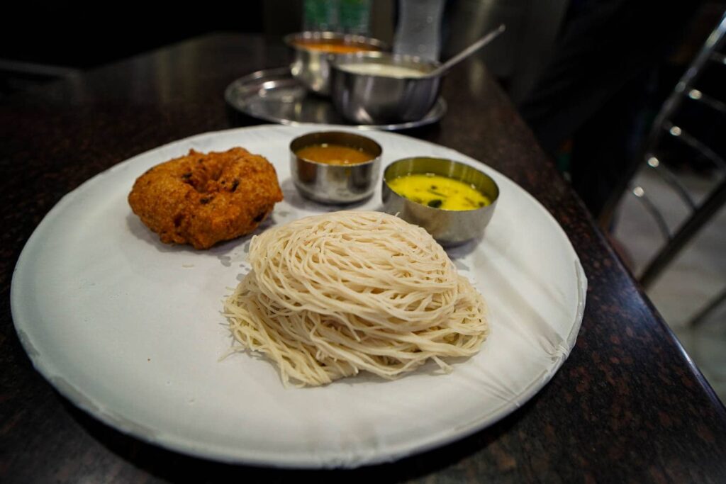 String hoppers on white plate with spicy dips