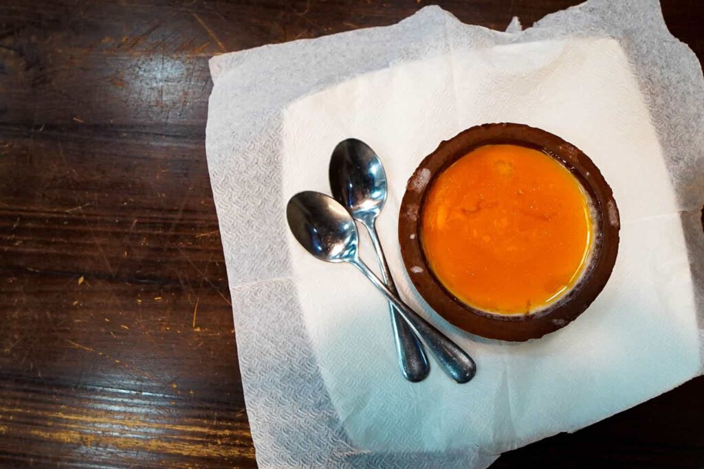 Clay pot of curd and treacle with two spoons on wooden table