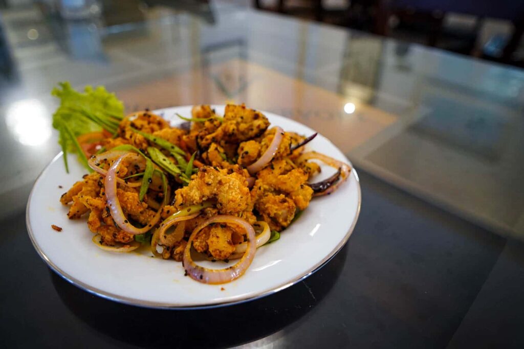 plate of orange hot butter cuttlefish on glass table sri lankan food