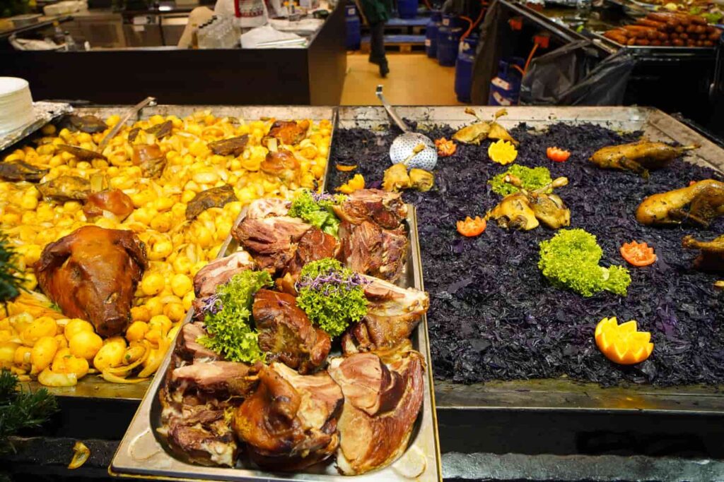 Three trays of Hungarian Chrismas food, yellow potatoes, black cabbage and large juicy cuts of pork.