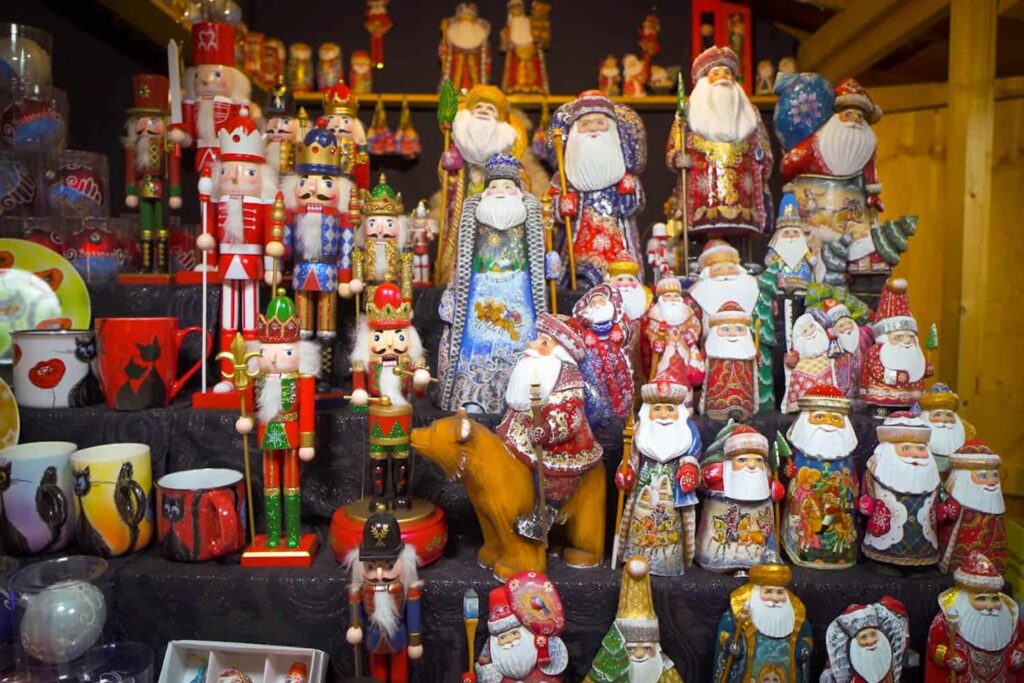 Rows of colourful, decorated Santa Clause ornaments on selves for sale at Christmas market in Europe.