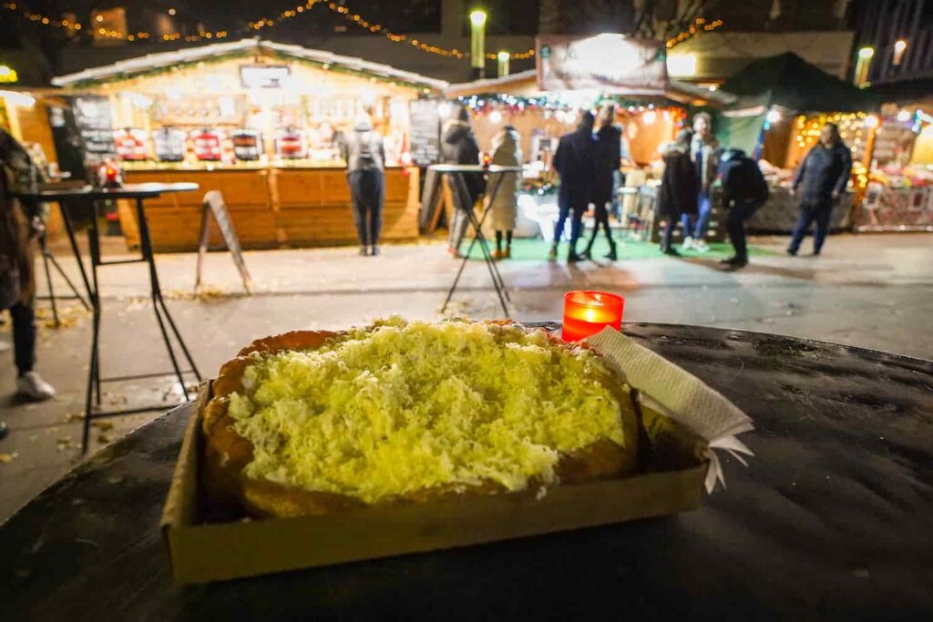 Cheesy langos sitting on a table at a local Christmas market in Europe.