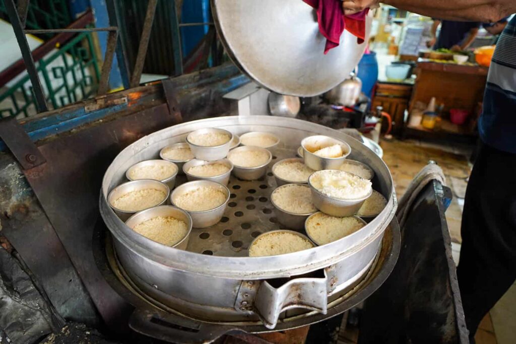 Steamed nasi tim chicken rice cooking in individual metal bowls at Nasi Tim Pasar Pagi in Jakarta Chinatown