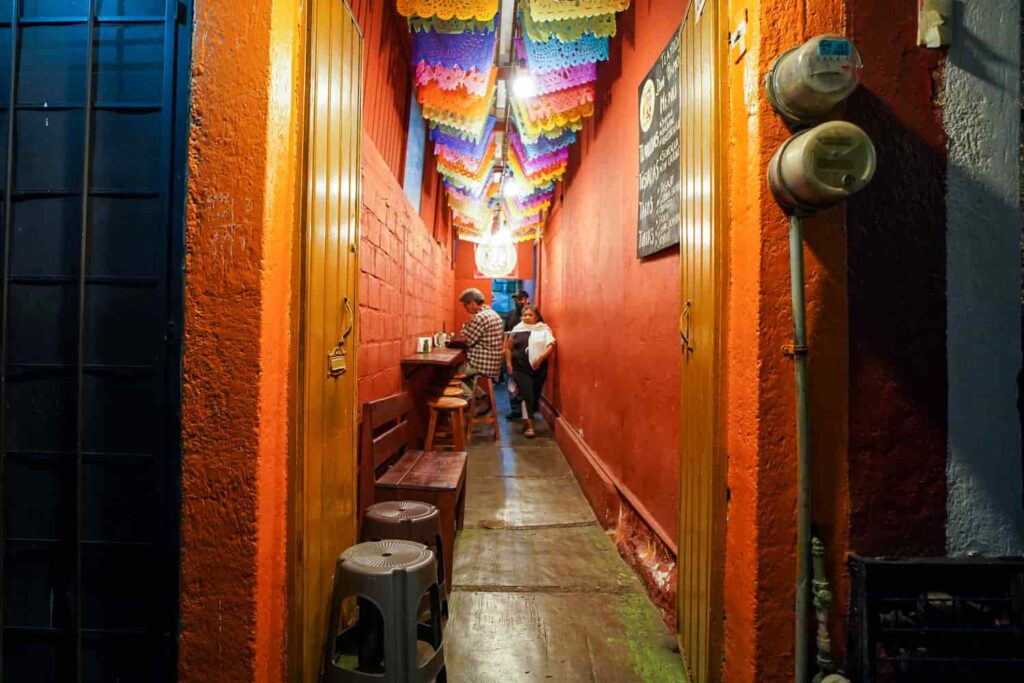 Interior view of Tlayudas Don Ramón, one of the best tlayuda spots in Oaxaca, showing its narrow seating area and long table with stools.