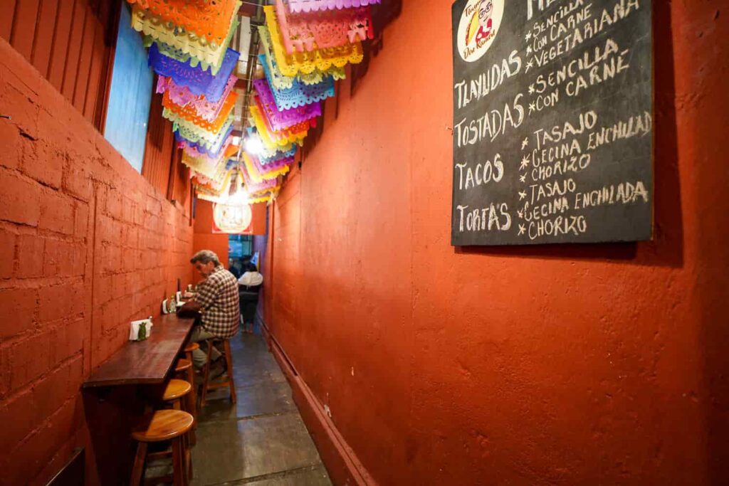 Inside Tlayudas Don Ramón in Oaxaca, with the blackboard menu and the narrow seating area visible.