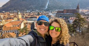 Hungry Two Travel smiling and taking a selfie with historic Brasov and black church in the background