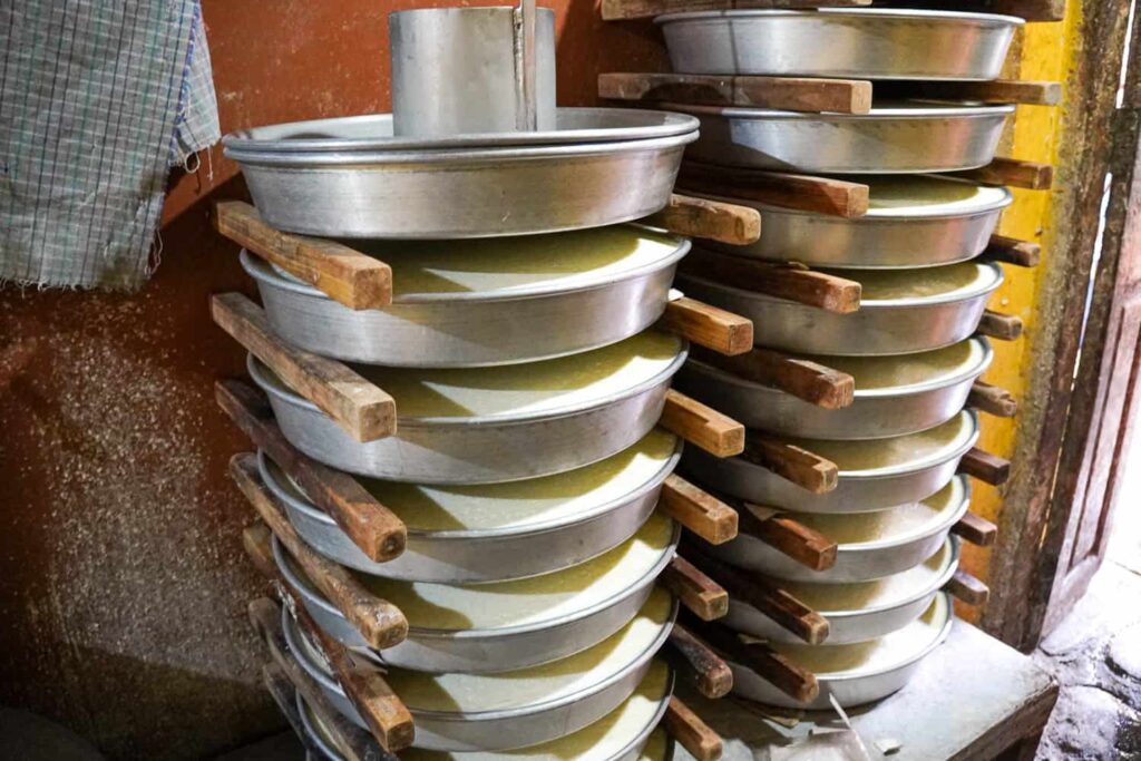 Stack of metal trays of homemade Indian yogurt being held up by wooden sticks